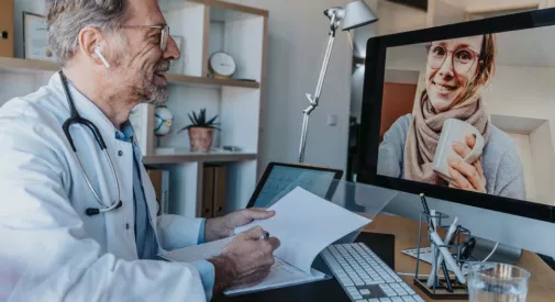 Arzt sitzt am Schreibtisch im Gespräch mit Patientin