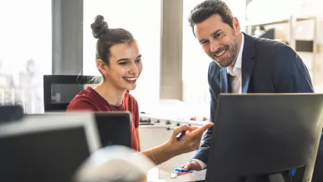 Frau und Mann schauen auf einen Computer